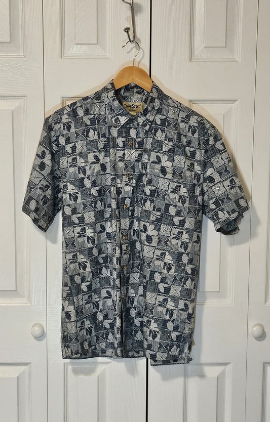 Short-sleeve shirt with geometric pattern on a hanger against a white door background